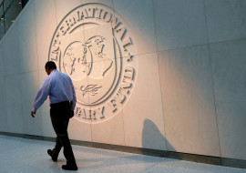 FILE PHOTO: Man walks past the IMF logo at HQ in Washington