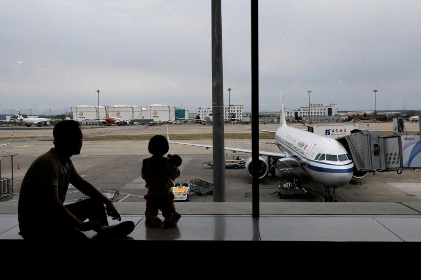FILE PHOTO: Passengers look at the tarmac as they wait for their flights at the Beijing Capital International Airport, in Beijing